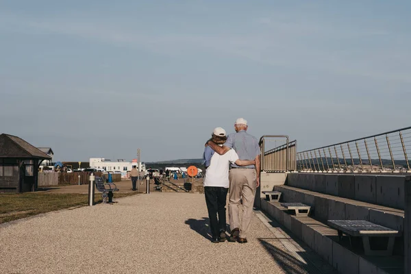 Couple sénior marchant les bras l'un autour de l'autre à Milford sur — Photo