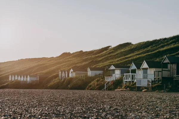 Cabanas de praia em Milford on Sea, Reino Unido, durante o pôr do sol . — Fotografia de Stock