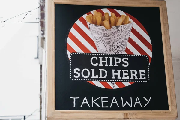 Chipsy, prodávané zde, si oddávají nápis mimo restauraci na ulici — Stock fotografie