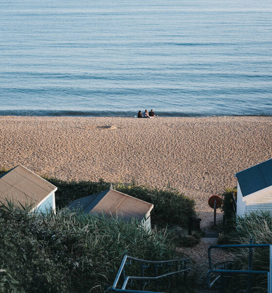 People relaxing on a beach by the huts at sunset in Milford on S Royalty Free Stock Photos