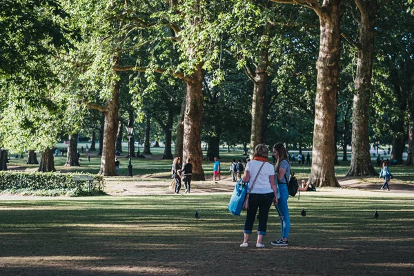 Personas que se relajan en un parque en un caluroso día de verano en Londres, Reino Unido . — Foto de Stock