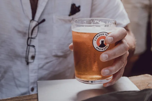 Man holding a glass of Camden Town Brewery beer, London, UK. — Stock Photo, Image