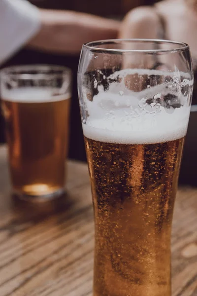 Biergläser auf einem Holztisch, Unbekannte auf dem Rücken — Stockfoto