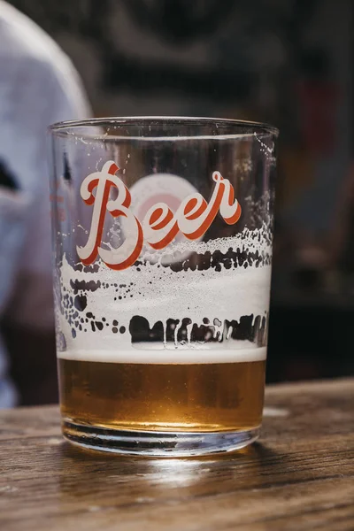 Beer glass with a modern "Beer" writing, on a wooden table, sele — Stock Photo, Image