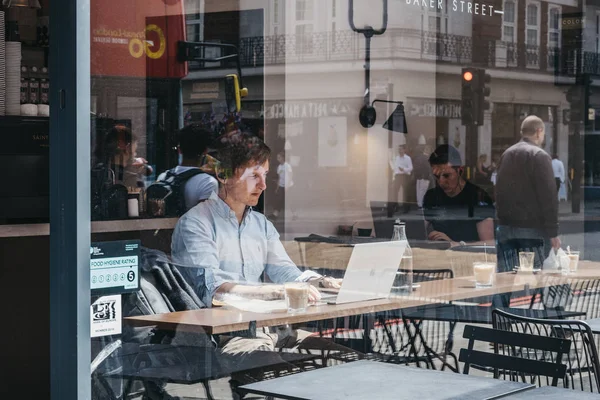 Através da janela de homens trabalhando em laptops dentro de um café em M — Fotografia de Stock