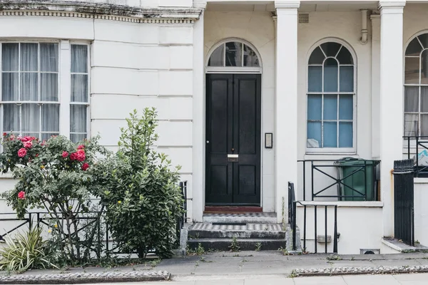Lon bir sokakta siyah giriş kapısı ile beyaz teraslı ev — Stok fotoğraf