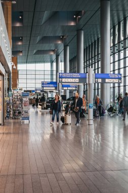 Luxembo terminalinde yön işaretlerinden geçen insanlar