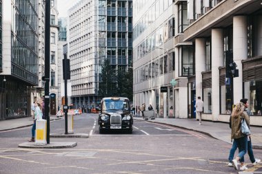 Londra 'da bir yolda siyah bir taksi trafik ışığını bekliyor, Uk..