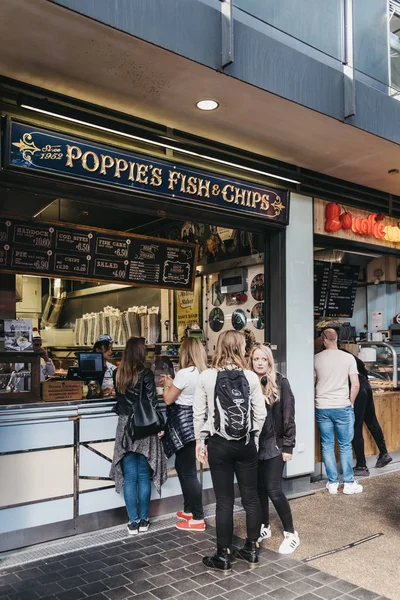 İnsanlar Haşhaş balığı ve patates kızartması sipariş ediyorlar.