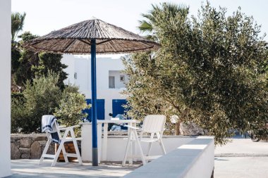 Yunanistan 'ın Mykonos kentinde sandalye, masa ve şemsiye.
