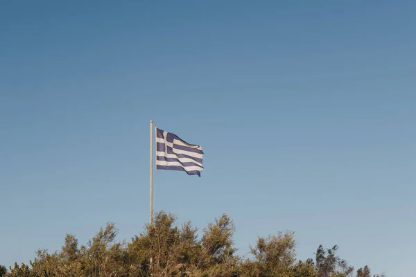 Greek flag in the wind, against blue sky.