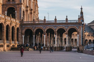 Seville, İspanya - 17 Ocak 2020: Plaza de Espana 'daki kemerler arasındaki insanlar, Seville, İspanya' daki Maria Luisa Parkı 'ndaki bir plaza, 1928 yılında 1929 yılında Ibero-Amerikan Sergisi için inşa edildi..