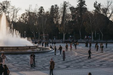Seville, İspanya - 17 Ocak 2020: Plaza de Espana 'daki çeşmenin yanında yürüyen insanlar, Ibero-Amerikan Sergisi için 1928 yılında inşa edilen Seville, İspanya' nın Parque de Maria Luisa şehrinde bir plaza..
