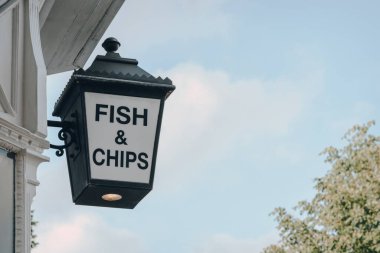 Londra, İngiltere 'de bir restoranın önündeki balık ve cips tabelalarının düşük açılı görüntüsü, gökyüzüne karşı, boşluğu kopyala.