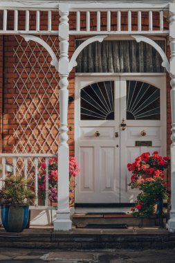 Londra, İngiltere - 26 Mayıs 2020: Londra 'daki Edwardian evinin beyaz camlı ön kapısı, güneş ışığı tuğla duvara çarpıyor. Edwardian evleri basit bir tasarım ve el yapımı için bir takdir sunar..