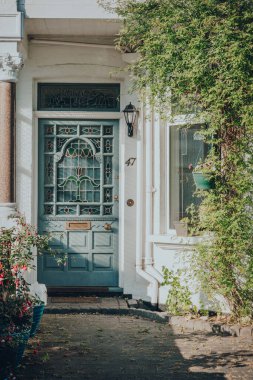 Londra, İngiltere - 26 Mayıs 2020: Londra 'daki Edwardian evinin Pastel boyalı ön kapısı, güneş ışığı ön cepheye vuruyor. Edwardian evleri basit bir tasarım ve el yapımı için bir takdir sunar..