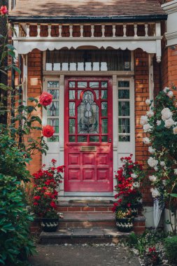 Londra, İngiltere - 30 Mayıs 2020: Londra 'daki geleneksel Edwardian evinin koyu pembe renkli ön kapısı, seçici odak noktası. Edwardian evleri basit bir tasarım ve el yapımı için bir takdir sunar..