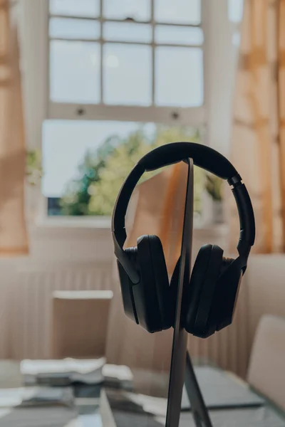 Black over ear headphones resting on a monitor, selective focus, work from home concept.