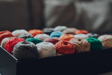 Bir kutu dolusu farklı renkte Amigurumi pamuk ipliği, seçici sığ odak.