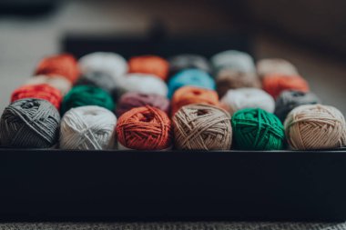 24 farklı renkte Amigurumi pamuğuyla dolu bir kutuyu kapat. En yakın satıra odaklan..