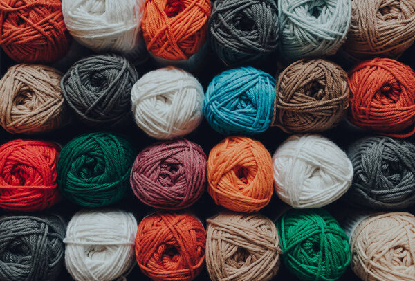 Overhead shot of rows of skeins of amigurumi cotton yarn in different colours, shallow focus.