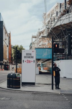 Londra, İngiltere - 13 Haziran 2020: Londra, İngiltere 'de ünlü ve tipik olarak işlek bir alışveriş caddesi olan boş New Oxford Caddesi' ndeki sosyal uzaklık tabelası.
