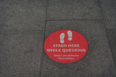 Londra, İngiltere 'de bir caddenin kaldırımında kırmızı tabela sırada beklerken burada dur..