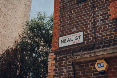 Londra, İngiltere - 13 Haziran 2020: Neal Street, Covent Garden 'da, Londra' nın barları, restoranları ve kafeleri ile ünlü olan tuğla bir binanın duvarında eski bir sokak ismi işareti.