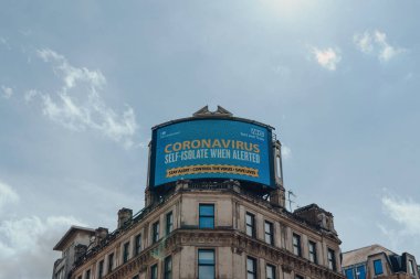 Londra, İngiltere - 13 Haziran 2020: Büyük dijital ekran ve Coronavirus güncellemesi Piccadilly Circus binasının tepesinde, Londra, İngiltere 'nin en yoğun ve en popüler turistik bölgelerinden biri.