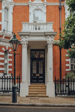 Londra, İngiltere - 20 Haziran 2020: Kensington 'daki geleneksel bir evin girişi, Batı Londra' da ünlülerin tercih ettiği zengin bir bölge. Seçici odak.