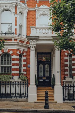 Londra, İngiltere - 20 Haziran 2020: Kensington 'daki geleneksel bir evin girişi, Batı Londra' da ünlülerin tercih ettiği zengin bir bölge. Seçici odak.