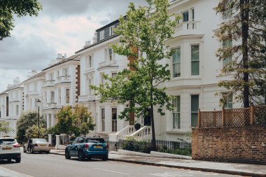 Londra, İngiltere - 20 Haziran 2020: Batı Londra 'nın ünlülerin tercih ettiği zengin bir bölge olan Holland Park' ta beyaz Victorian evleri olan sakin bir yerleşim yeri manzarası.