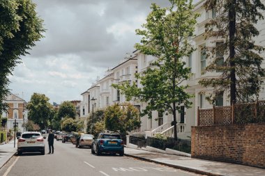 Londra, İngiltere - 20 Haziran 2020: Batı Londra 'da ünlülerin tercih ettiği zengin bir bölge olan Holland Park' taki beyaz Viktorya dönemi evlerinin önüne park edilmiş arabalar.