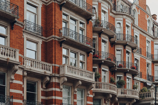 Exterior of a traditional red brick apartment block with balconies in Kensington and Chelsea, London, UK.