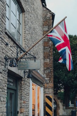 Stow-on-the-Wold, İngiltere - 6 Temmuz 2020: Cotswolds 'da Roman Fosse Yolu üzerinde inşa edilen bir pazar kasabası olan Stow-on-the-Wold' daki bir kır evinin cephesinde Union Jack bayrağı.