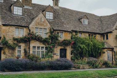 Broadway, İngiltere - 07 Temmuz 2020: Worcestershire, İngiltere 'de Cotswolds içinde büyük tarihi bir köy olan Broadway' de geleneksel bir kireçtaşı evinin cephesi ve ön bahçesi.