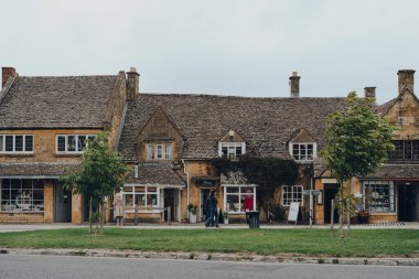Broadway, İngiltere - 07 Temmuz 2020: Broadway 'de High Street' teki dükkanlar, Worcestershire, İngiltere 'de Cotswolds' da tarihi bir köy ve sivil bir kilise, insanlar yanından geçiyor.