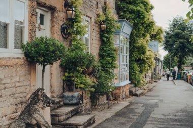 Stow-on-the-Wold, İngiltere - 10 Temmuz 2020: Stow-the-Wold 'da ana caddede bir dizi ev, arka planda bazı yerel sakinler. Cotswolds, İngiltere 'de Roman Fosse Yolu üzerine kurulmuş bir pazar kasabası kurun..