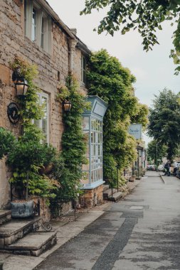Stow-on-the-Wold, İngiltere - 10 Temmuz 2020: Cotswolds, İngiltere 'de Roman Fosse Yolu üzerine inşa edilmiş bir pazar kasabası olan Stow-on-the-Wold' un ana caddesindeki evler, yerel dükkanlar ve kafe.