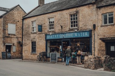 Bourton-on-the-Water, İngiltere - 12 Temmuz 2020: İnsanlar İngiltere 'nin Cotswolds kırsalındaki ünlü bir köy olan Bourton-on-the-Water' daki fırının vitrinindeki ürünlere bakıyorlar.