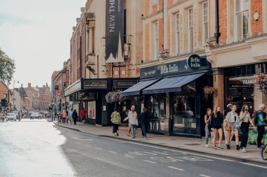 Oxford, İngiltere - 4 Ağustos 2020: İngiltere 'nin prestijli üniversitesi ile ünlü Oxford' da bir caddedeki restoranların önünden geçen insanlar, 12. yüzyılda kuruldu..