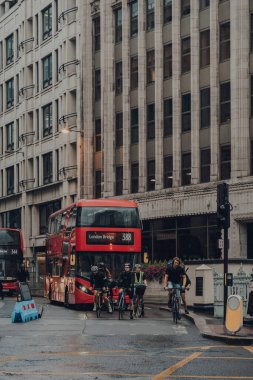 Londra, İngiltere - 24 Ağustos 2020: Yaz günü Tower Bridge 'den tarihi bir finans bölgesi olan Londra şehrinde trafik ışığı bekleyen bisikletçiler ve kırmızı otobüs.