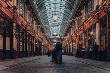 Londra, İngiltere - 24 Ağustos 2020: 19. yüzyılda Londra 'da inşa edilmiş olan Leadenhall Market' in atari salonunda tek başına duran bir adamın dikiz görüntüsü.