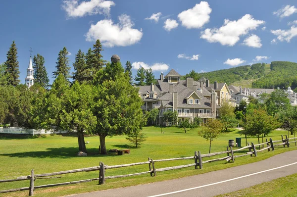 Mont Tremblant Kanada - 16 Temmuz 2013: Yazın Mont Tremblant Köyü 'nün önünde bir park ve otel binaları ve arka planında Mont Tremblant Dağı ile birlikte. 