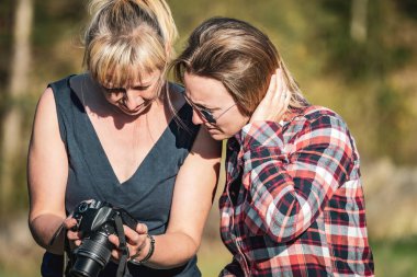 İki kadın yazın dijital lens refleks kamerasında fotoğraflara bakıyor.