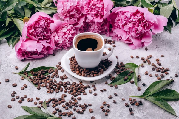 Zwarte koffie in een witte kop en roze-gekleurde pioenrozen Stockfoto