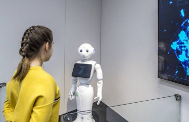 Vantaa, Helsinki, Finland - March 30, 2018: Pepper robot, assistant with Information screen at Heureka is Finnish science center (main scientific museum of Scandinavia) and female in yellow clipart