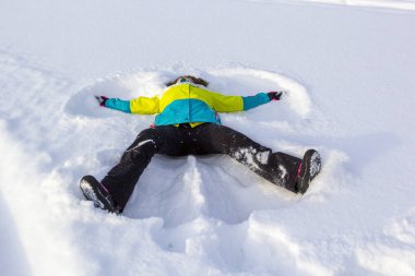 Neşeli ve mutlu kız yalan kar ve kar melek yapma, kollarını ve bacaklarını farklı yönlere çırparak zevk ve sevindirici kış.