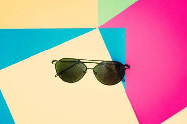 Renkli kağıt zemin üzerinde şık siyah güneş gözlüğü. Doku arka plan moda renk: pembe, sarı, yeşil, mavi. Düz yatıyordu moda seti, en az style, üstten görünüm.