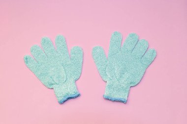 Banyo duş için mavi eldiven ile fırçalayın etkisi yumuşak pembe bir arka plan üzerinde peeling peeling hidro masaj. Üstten Görünüm, düz yatıyordu.